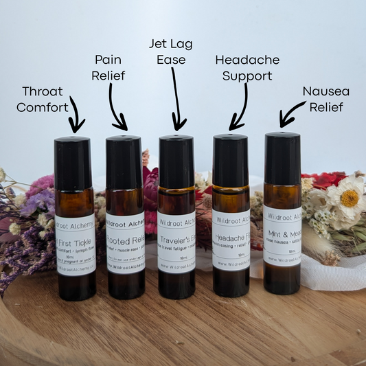 Five small bottles of essential oil blends on a wooden surface with labels indicating their uses.