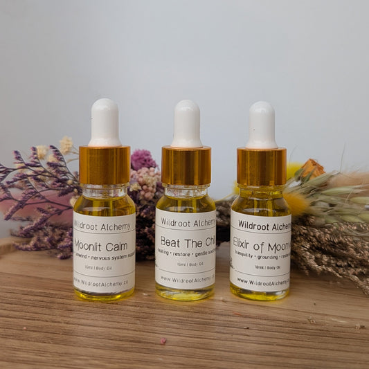 Three dropper bottles with labels on a wooden surface with dried plants in the background