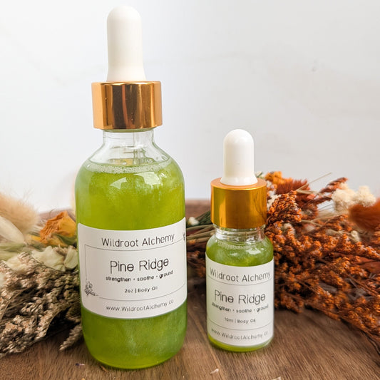 Two bottles of Wildroot Alchemy Pine Ridge product on a wooden surface with dried plants.