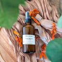 Brown bottle with a label on a beige fabric background with dried flowers