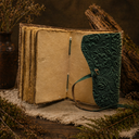 Open book with textured green cover on a wooden surface with plants