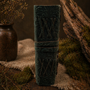 Decorative green vase with intricate patterns on a rustic surface with plants.