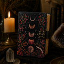 Decorative notebook with moon phases design on a mystical setting with candles and crystals.