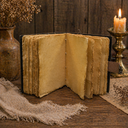 Vintage open book on a wooden surface with a candle and vase in the background