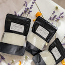 Three black bags with white contents on a marble surface with lavender and orange flowers.