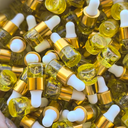 Small glass bottles with yellow liquid and white caps in a wooden bowl.