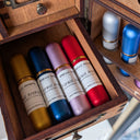 Wooden box with colorful bottles labeled 'Forest Alchemy' on a wooden shelf.