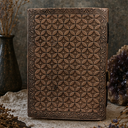 Brown leather notebook with geometric pattern on a textured surface with decorative elements.