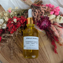 Bottle of Wildroot Alchemy Botanical Quench on a wooden surface with dried flowers.