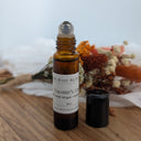 Bottle of Wildroot Alchemy 'Traveler's Ease' on a wooden surface with dried flowers in the background.