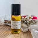 Bottle of Wildroot Alchemy Golden Facial Ease on a wooden surface with flowers in the background