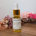 Bottle of Wildroot Alchemy Elixir of Moonlight with dried flowers on a wooden surface