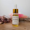 Bottle of Fae Nectar from Wildroot Alchemy on a wooden surface with flowers in the background