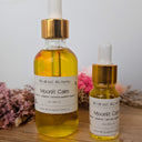 Two bottles of Wildroot Alchemy Moonlit Calm on a wooden surface with flowers in the background.