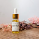 Bottle of Wildroot Alchemy Botanical Quell on a wooden surface with flowers in the background