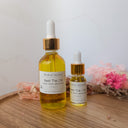 Two bottles of 'Beat The Chil' by Wildroot Alchemy on a wooden surface with dried flowers in the background.