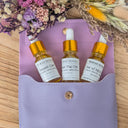 Three dropper bottles on a purple pouch with dried flowers in the background