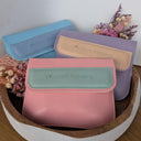 Three small pouches in pink, blue, and purple with 'Wildroot Alchemy' branding on a white background.