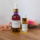 Two bottles of Wildroot Alchemy extract on a wooden surface with dried flowers in the background.