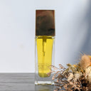 Perfume bottle with gold cap on a wooden surface with dried flowers