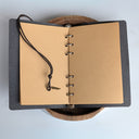 Open notebook with leather cover and black strap on a light gray background