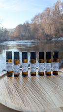 Set of small brown bottles with labels on a wooden surface near a body of water.